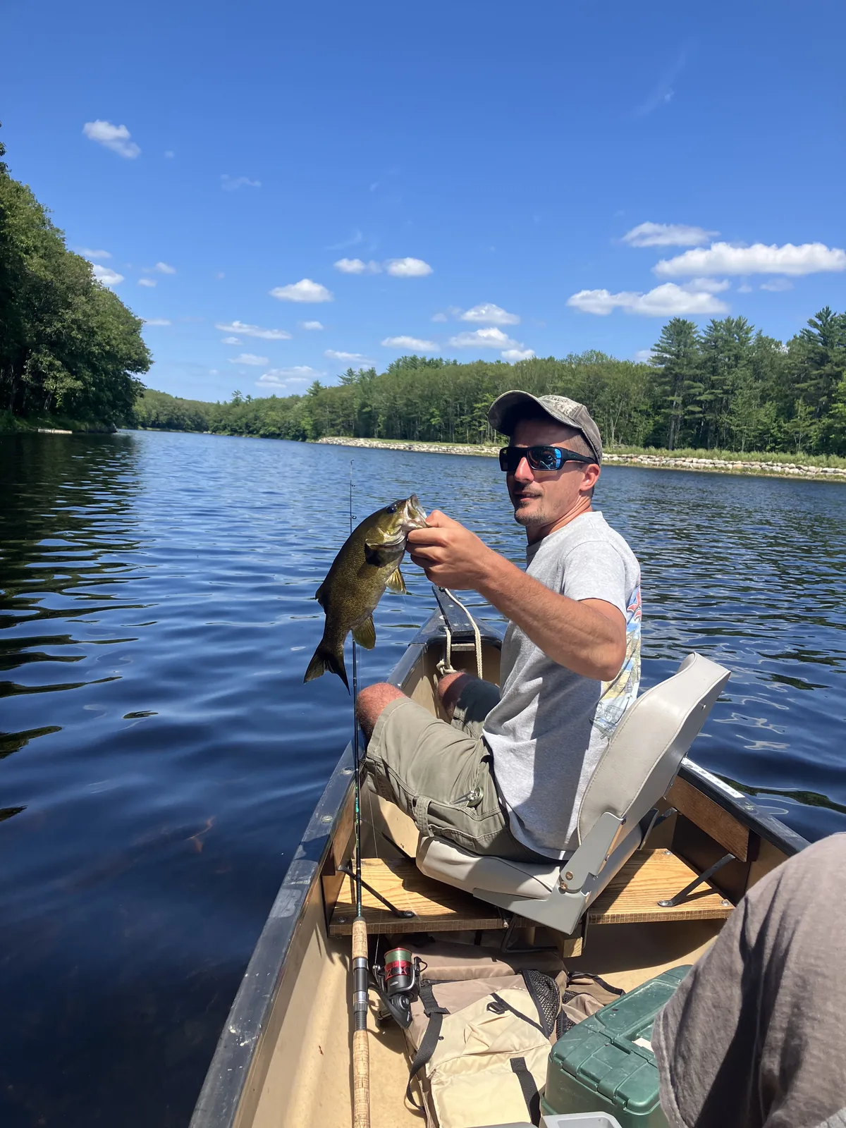 Client holding a bass while fishing from a canoe