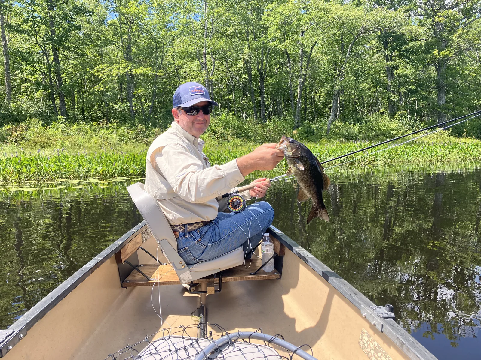 Client holding a bass during a guided canoe fishing trip