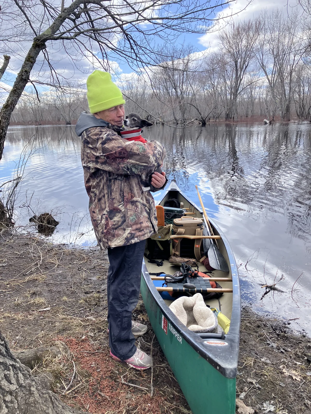 Client holding a small dog beside a canoe during a Maine guided trip