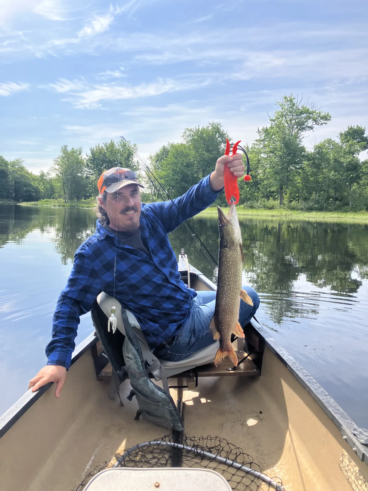 Client holding a fish during a guided fishing trip from a canoe