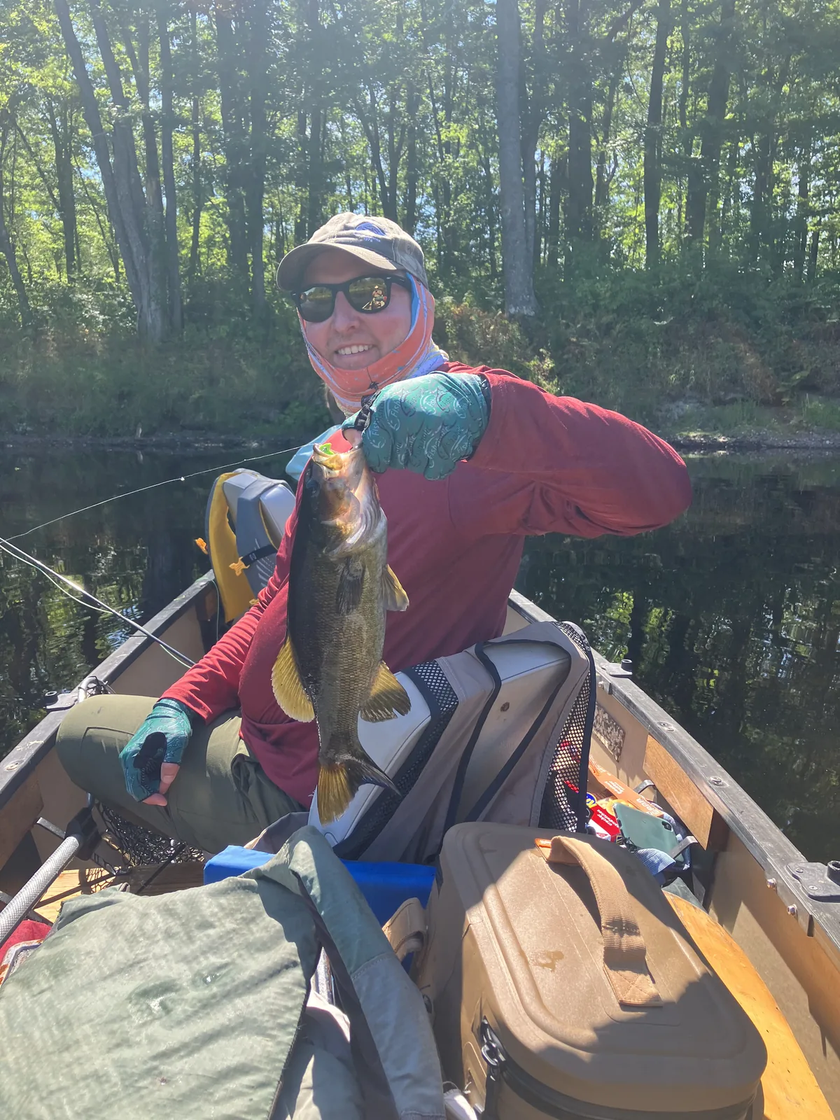 Client holding a fish from a canoe during a guided Maine fishing trip