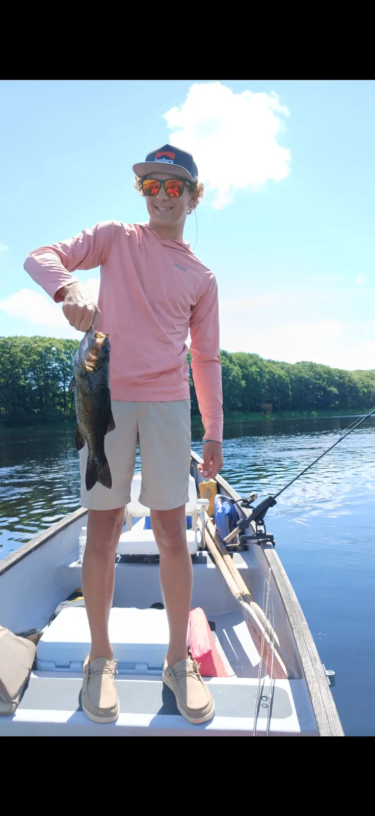 Client standing in a canoe during a guided Maine fishing trip