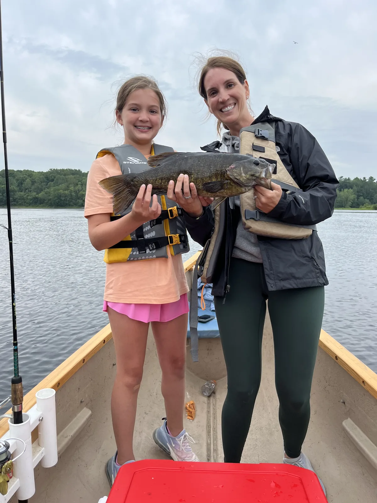 Family members holding a smallmouth bass during a guided Maine fishing trip
