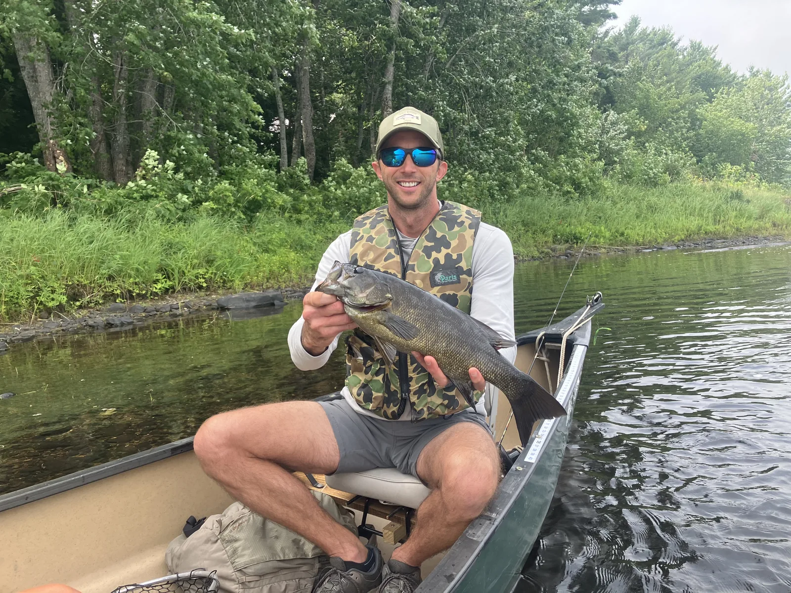 Client holding a smallmouth bass while seated in a canoe