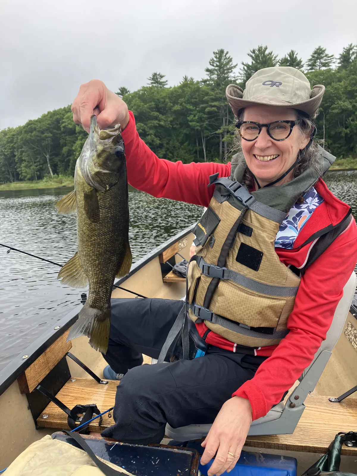 Client holding a smallmouth bass while seated in a canoe