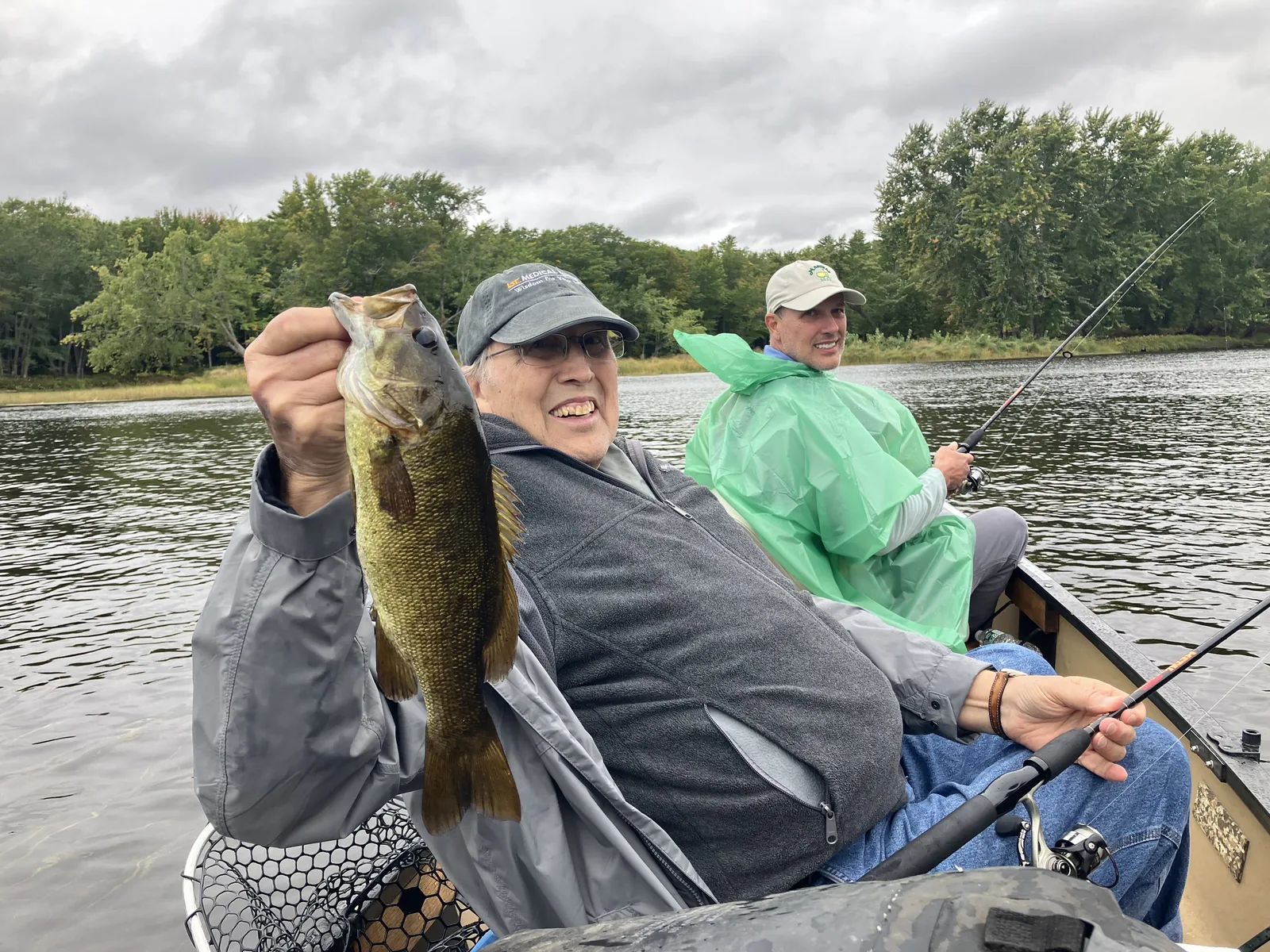 Client holding a smallmouth bass while fishing from a canoe