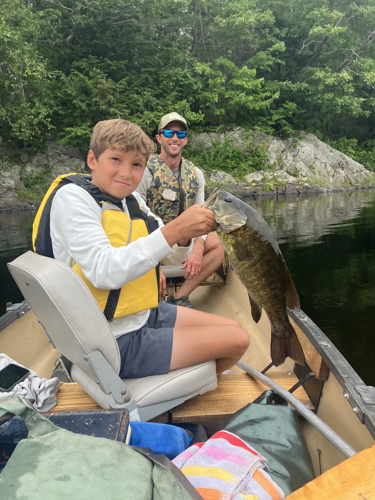 Young angler holding a smallmouth bass during a guided canoe fishing trip