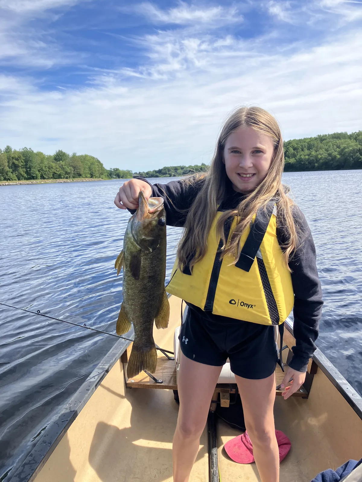 Young angler holding a smallmouth bass while seated in a canoe