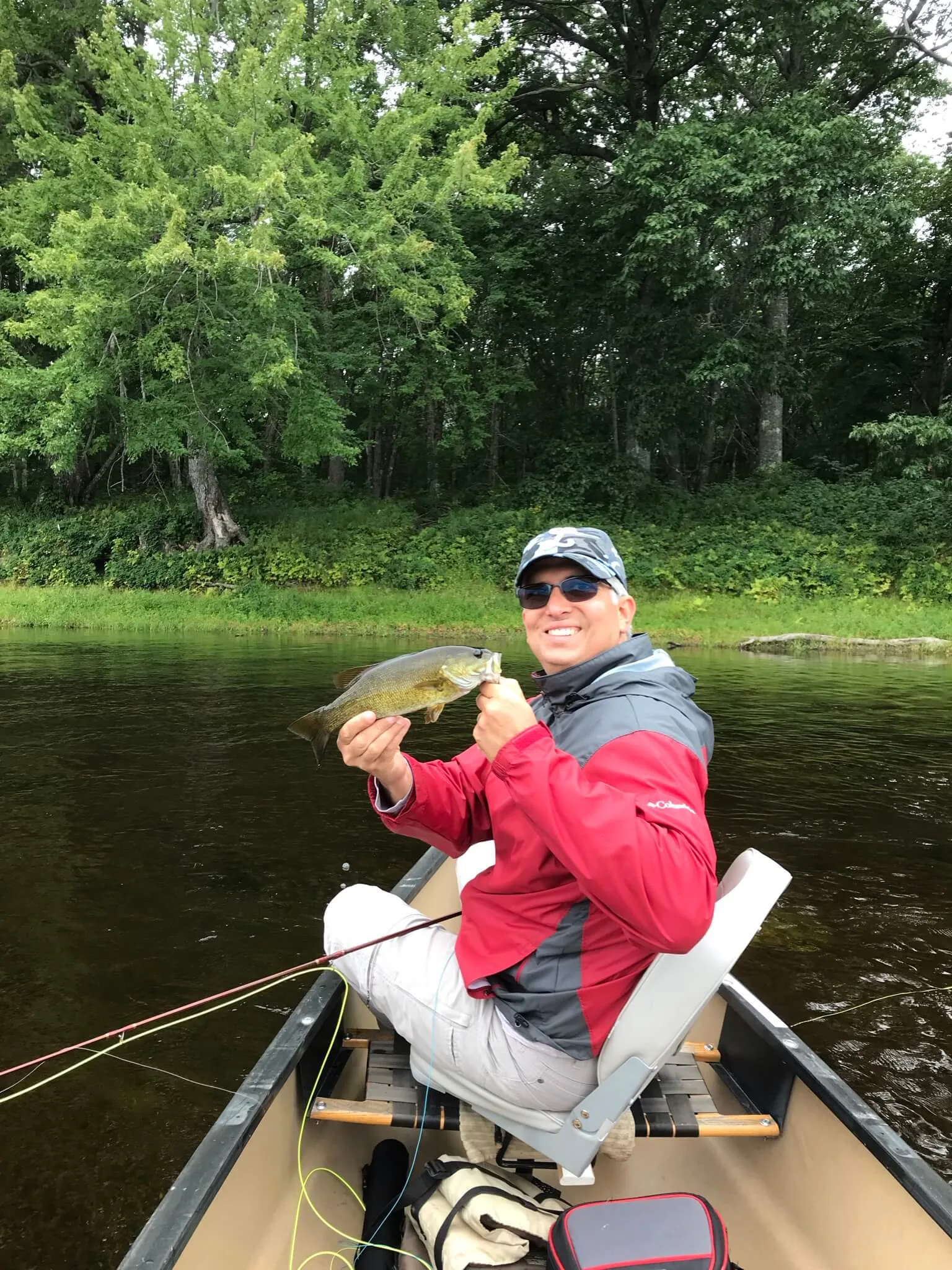Client holding a smallmouth bass while fishing from a canoe