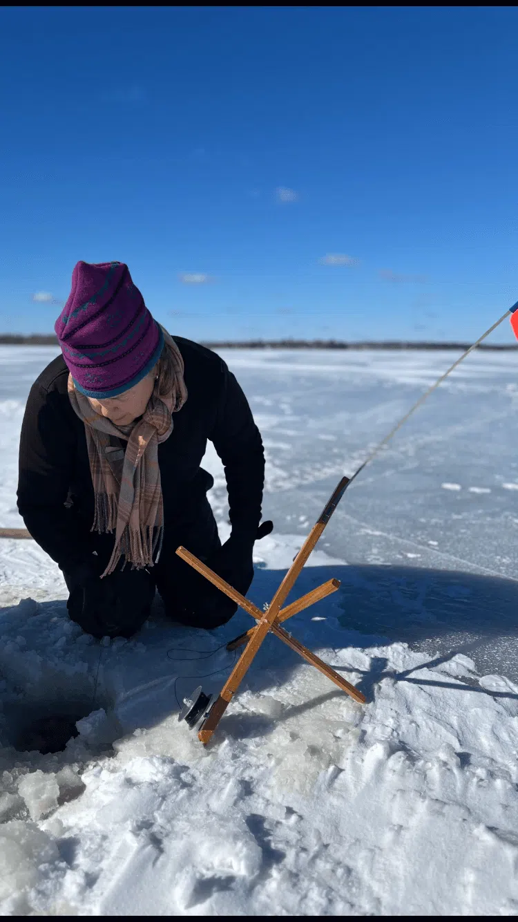 Client tending an ice fishing trap on a frozen Maine lake
