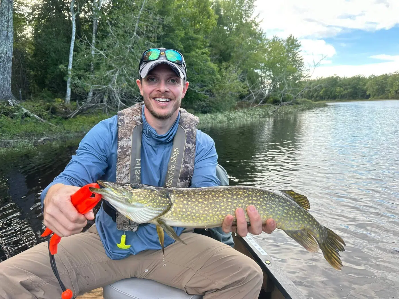 Smiling client holding a northern pike during a guided canoe fishing trip