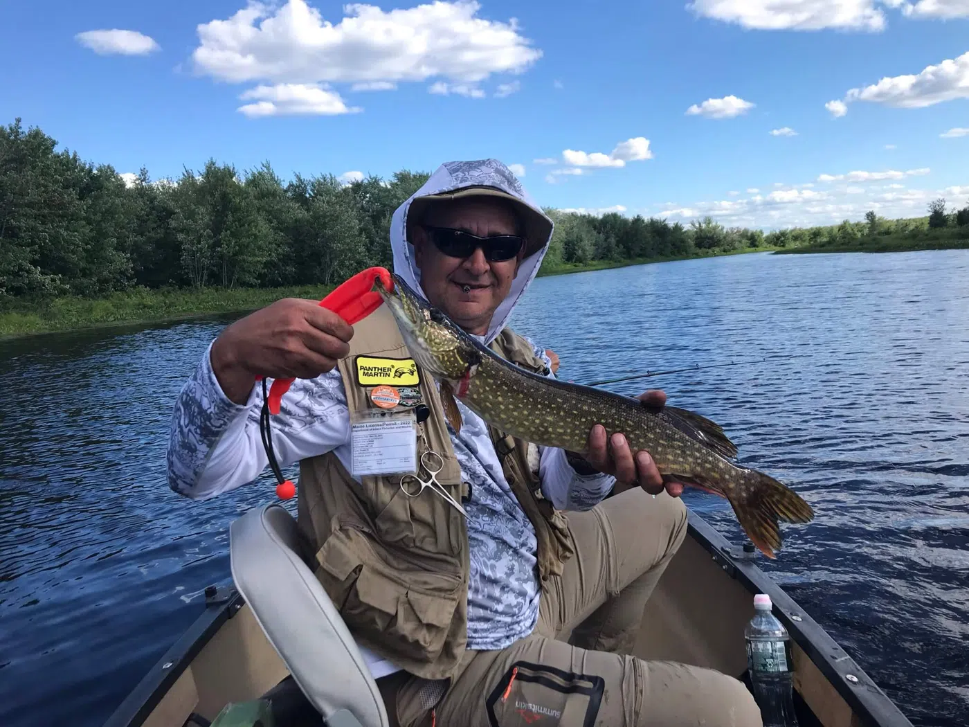 Client holding a fish from a canoe during a guided Maine fishing trip