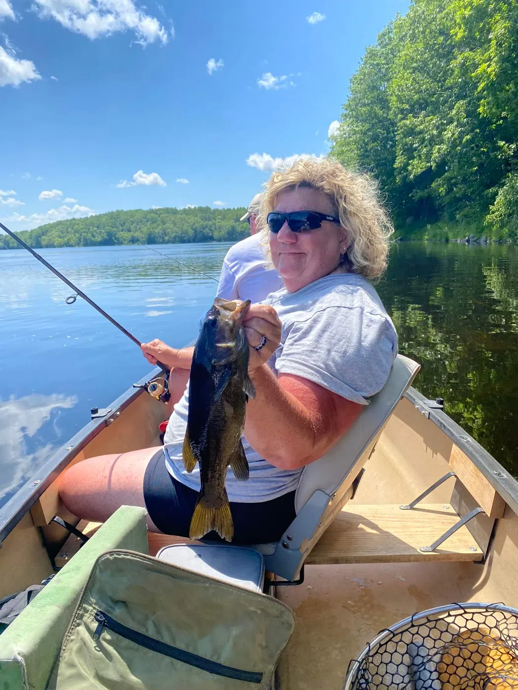Client holding a bass while seated in a canoe