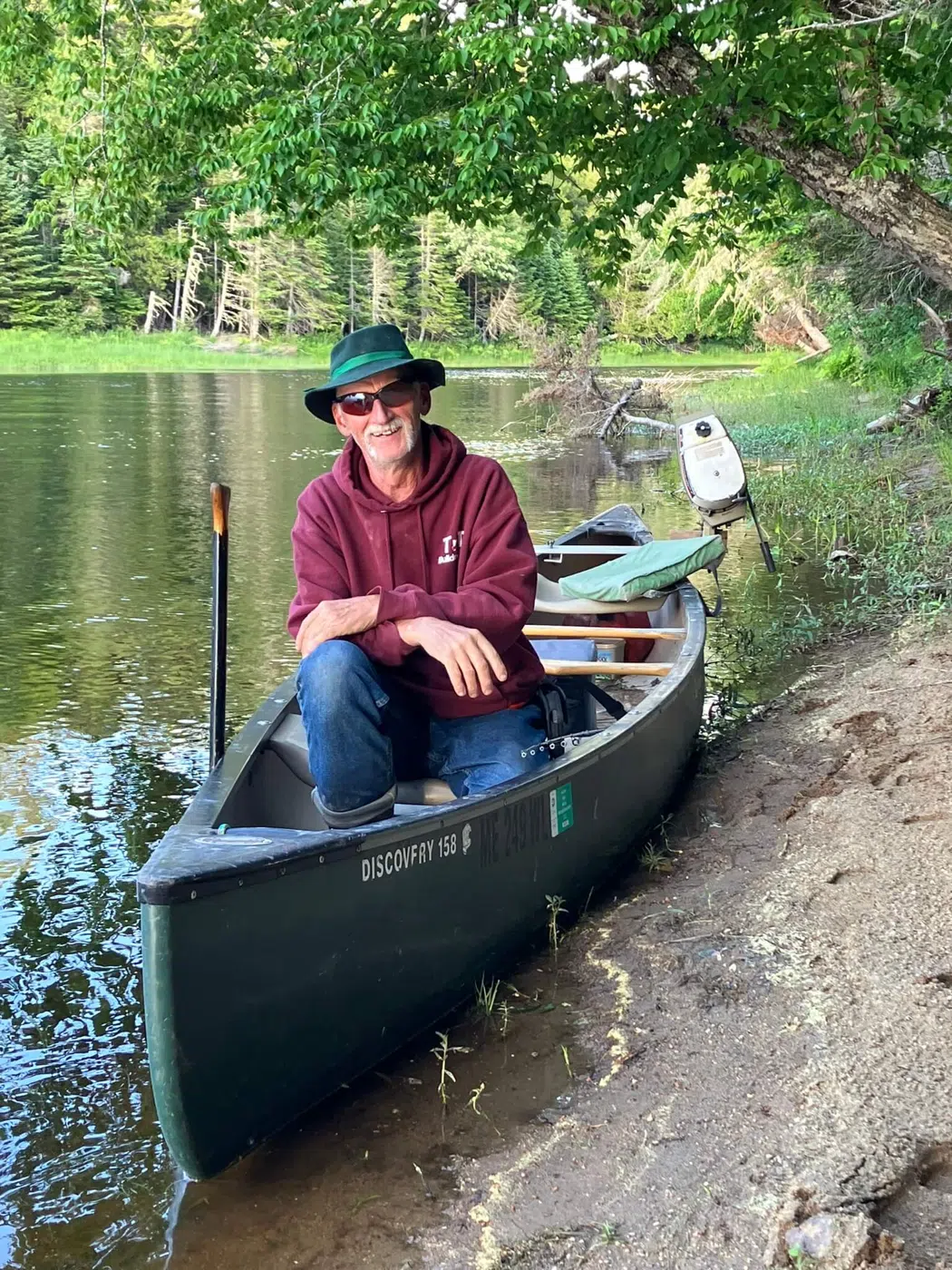 Client seated in a canoe beside a Maine riverbank