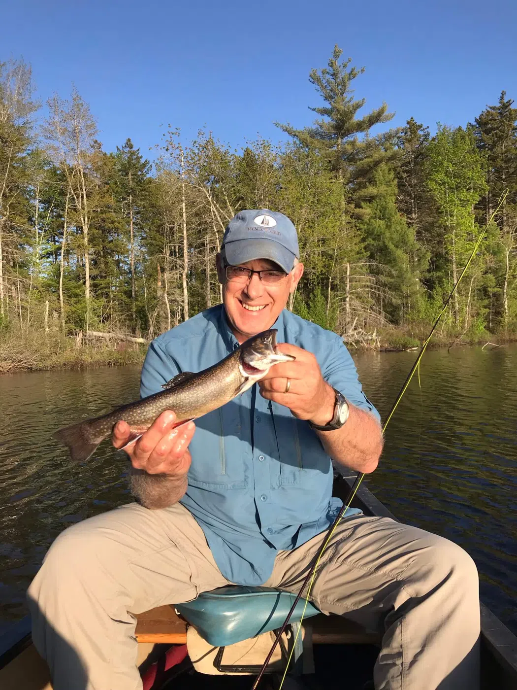 Client holding a smallmouth bass while seated in a canoe