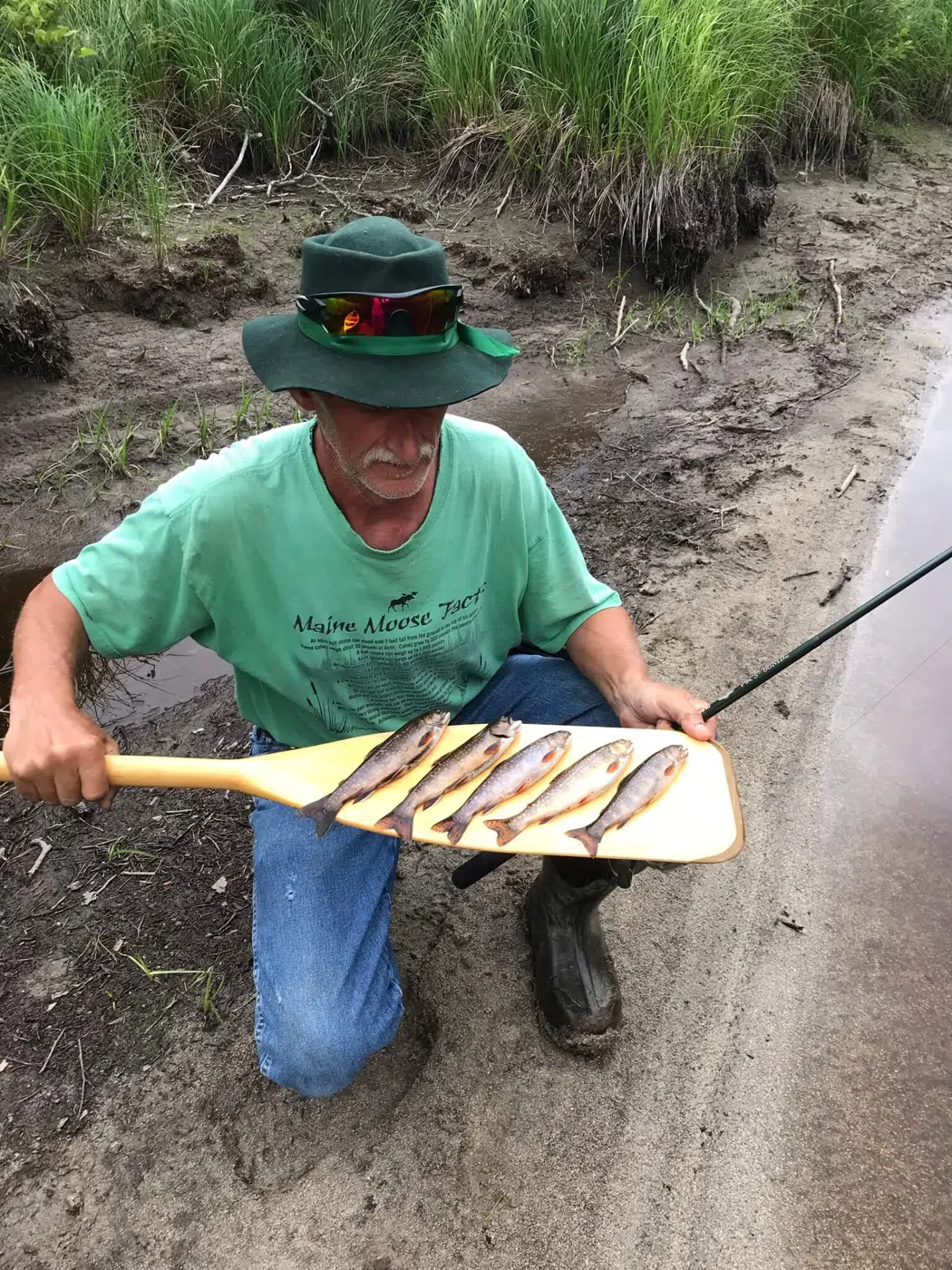 Client displaying a stringer of fish beside a Maine river
