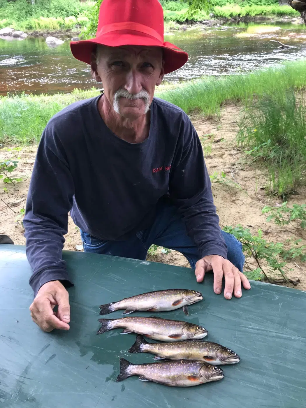 Client displaying a catch on a table beside the water
