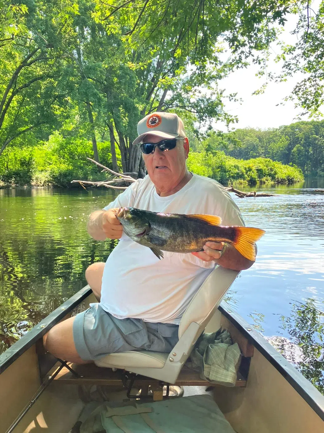 Client holding a large smallmouth bass from a canoe