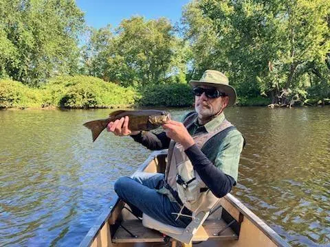 Client holding a fish while seated in a canoe