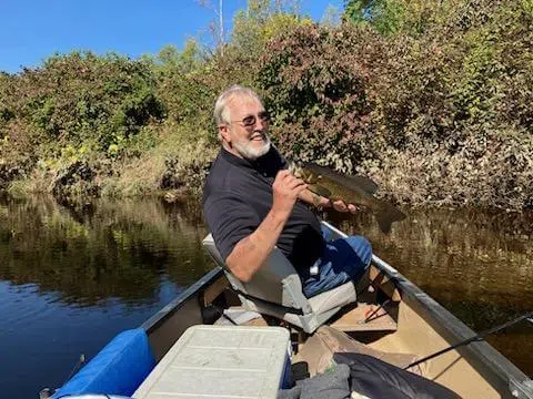 Client holding a fish from a canoe during a guided trip
