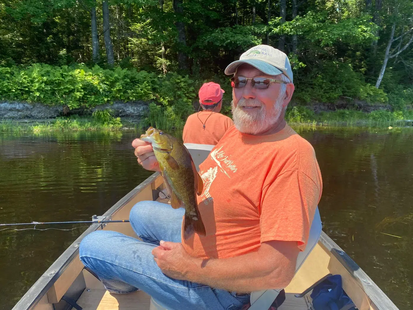 Client holding a bass while seated in a canoe