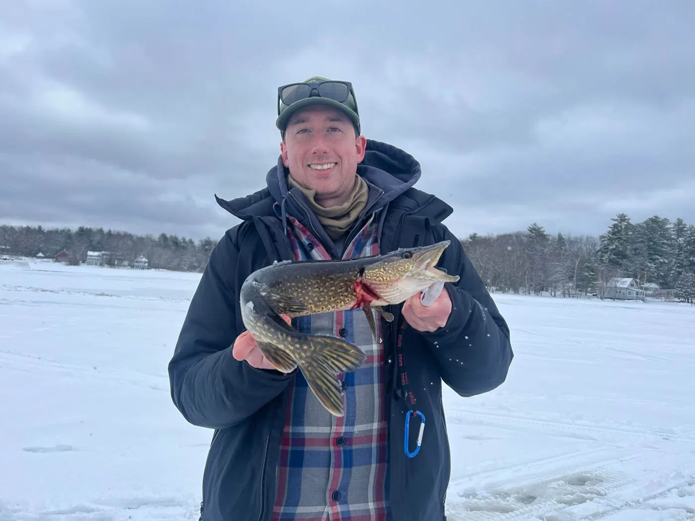 Client holding a fish during a Maine ice fishing trip