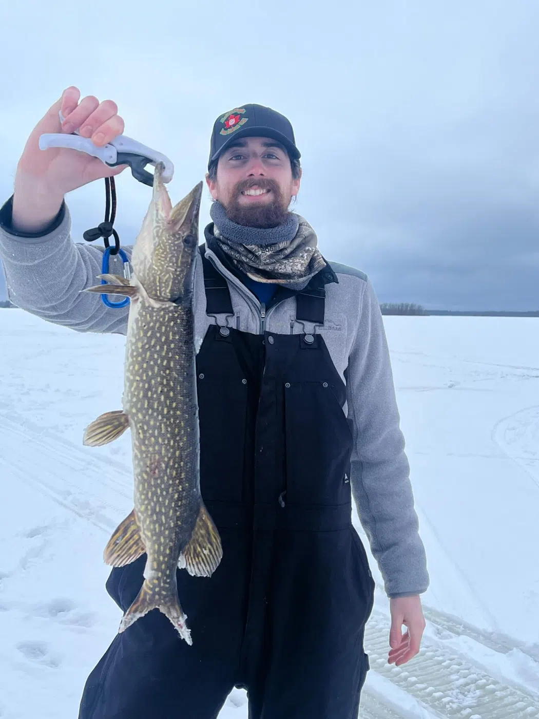 Client holding a large fish on a frozen Maine lake