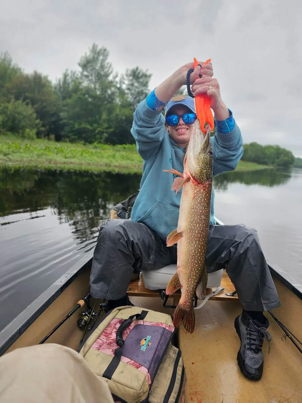 Client holding a northern pike during a guided canoe fishing trip