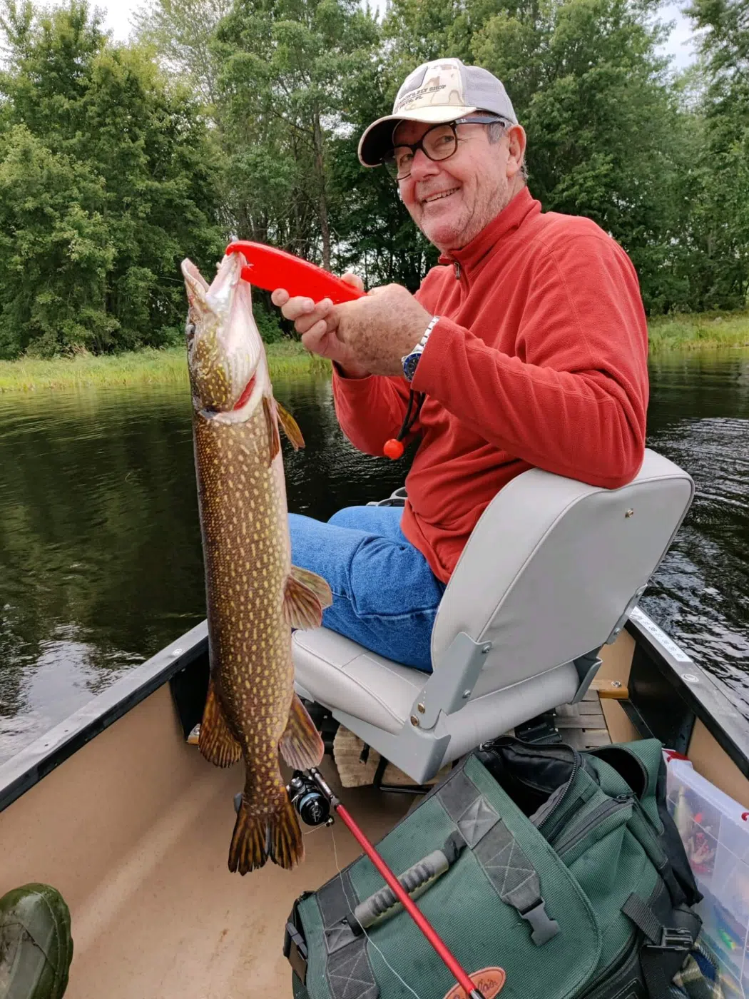 Client holding a northern pike from a canoe
