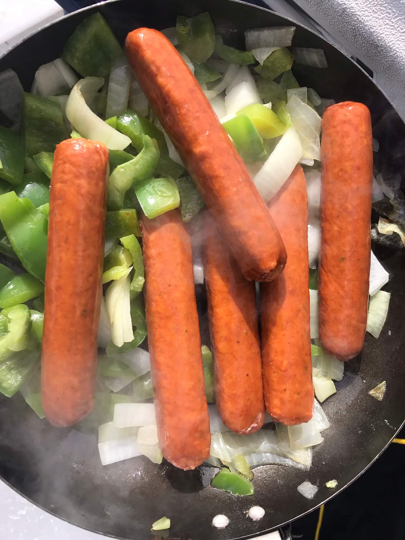 Cooking, hotdogs, onions, and green peppers